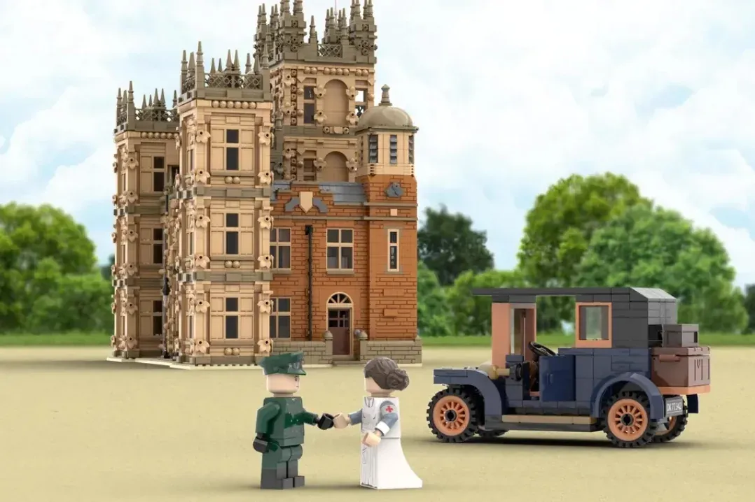 LEGO Downton Abbey set featuring ornate mansion, vintage automobile, and two minifigures on sandy ground.