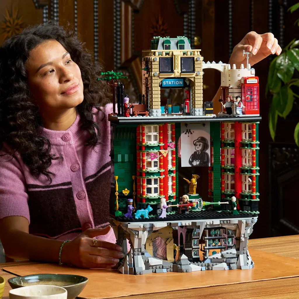 Woman presenting LEGO Harry Potter Ministry of Magic set with red phone booth and detailed brick buildings.