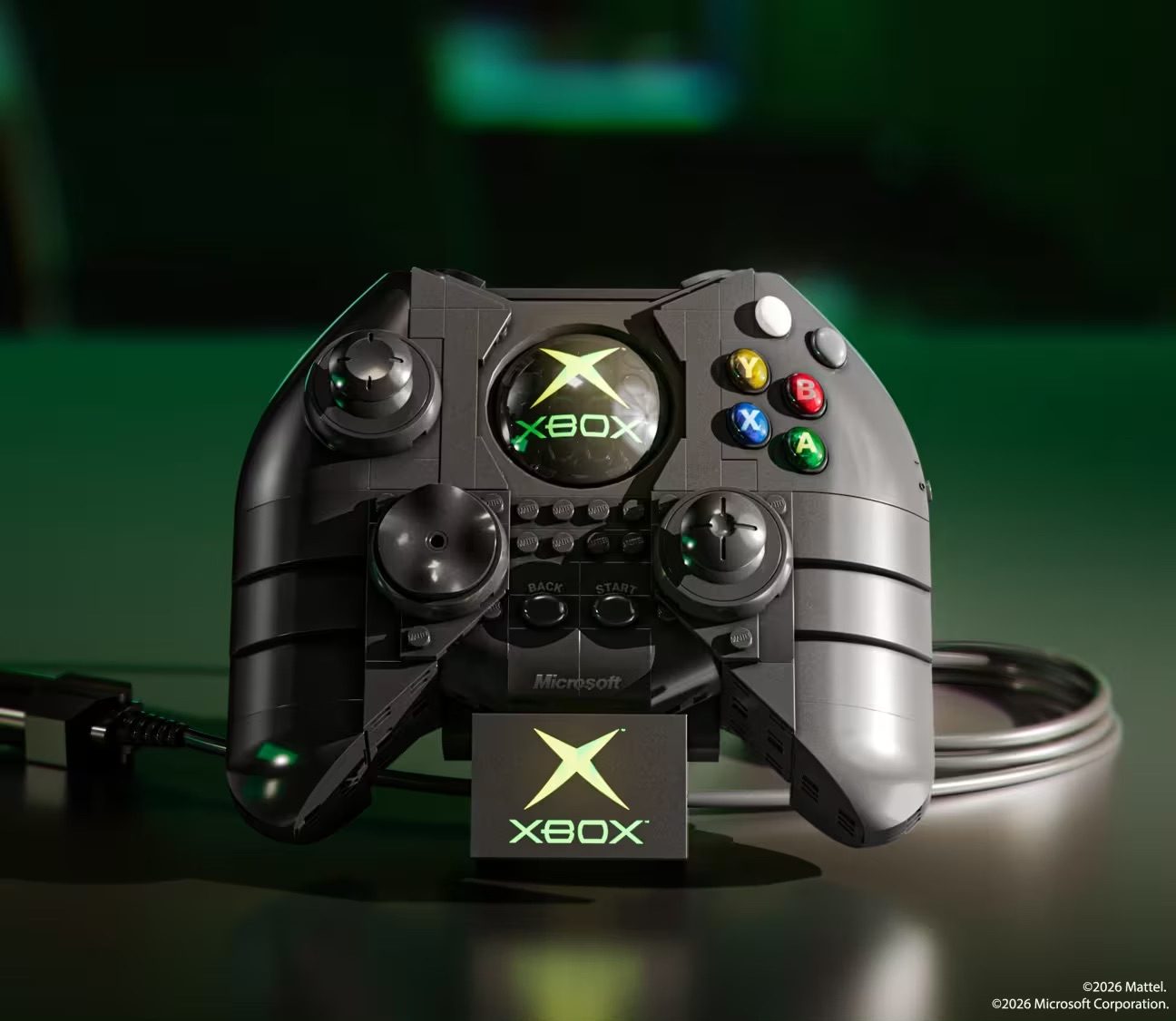 LEGO Xbox controller set displayed with illuminated X logo and colored buttons on green surface.
