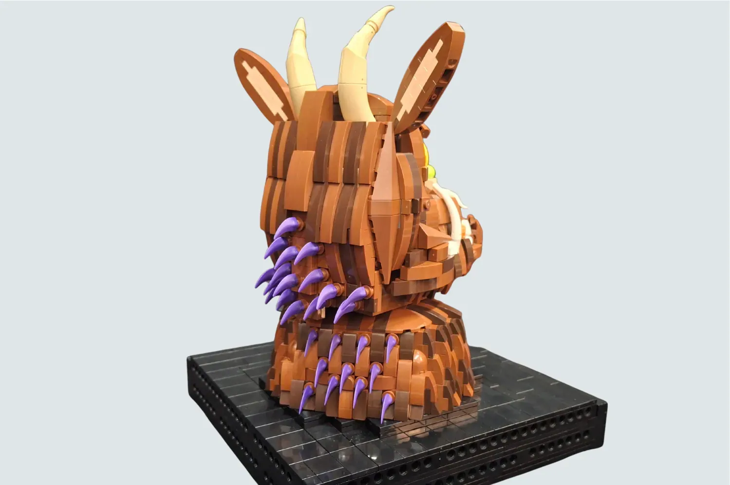 LEGO Gruffalo bust with purple claws, ivory tusks, layered brown body on black base.
