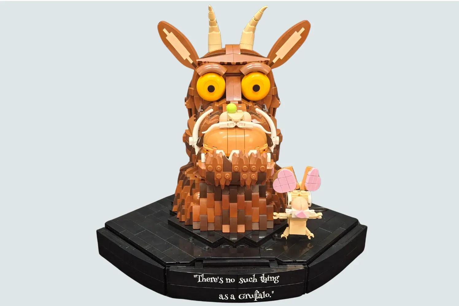 LEGO Gruffalo set with brown creature figure, yellow eyes, open mouth, small mouse minifigure, on black hexagonal base wit…