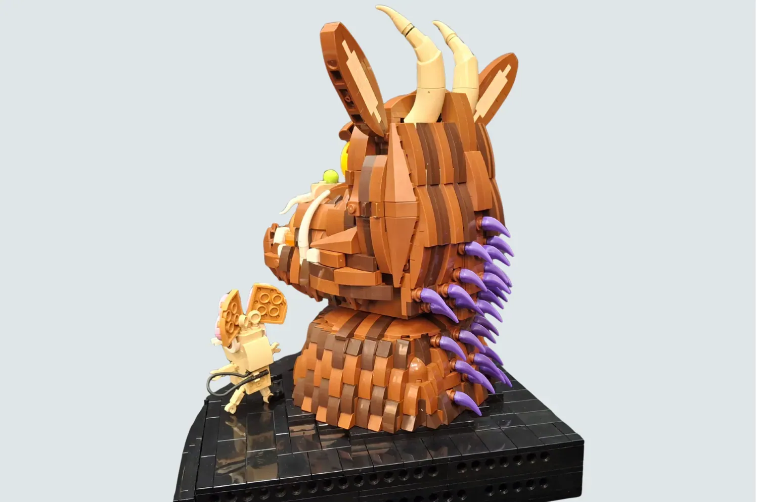 LEGO Ideas Gruffalo bust sculpture with purple claws, holding books on black base.