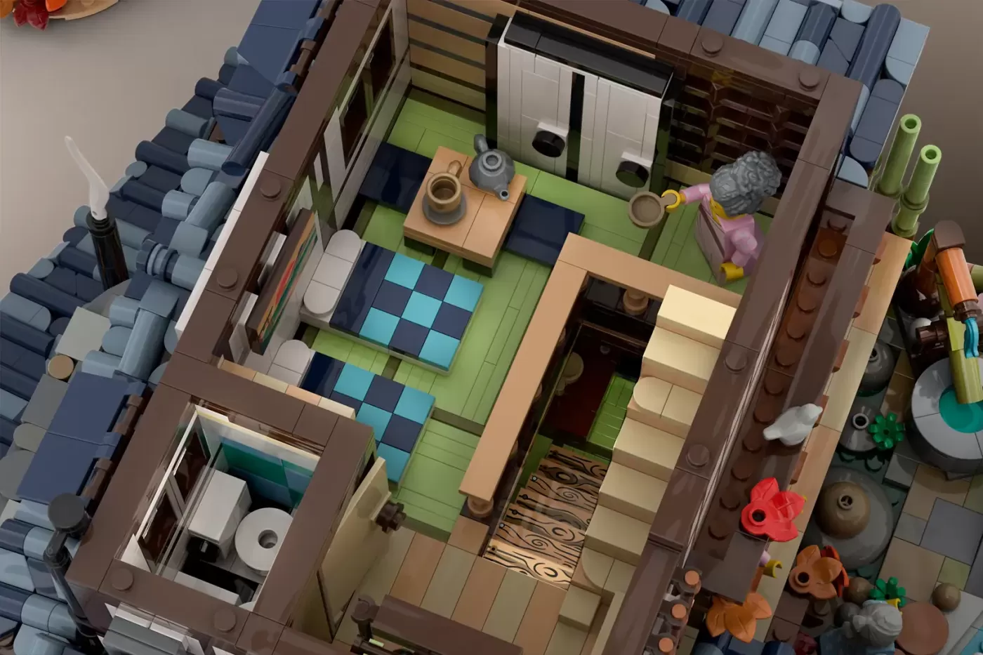 LEGO Japanese onsen building with green floors, brown walls, miniature furniture, and autumn decorations visible from above.