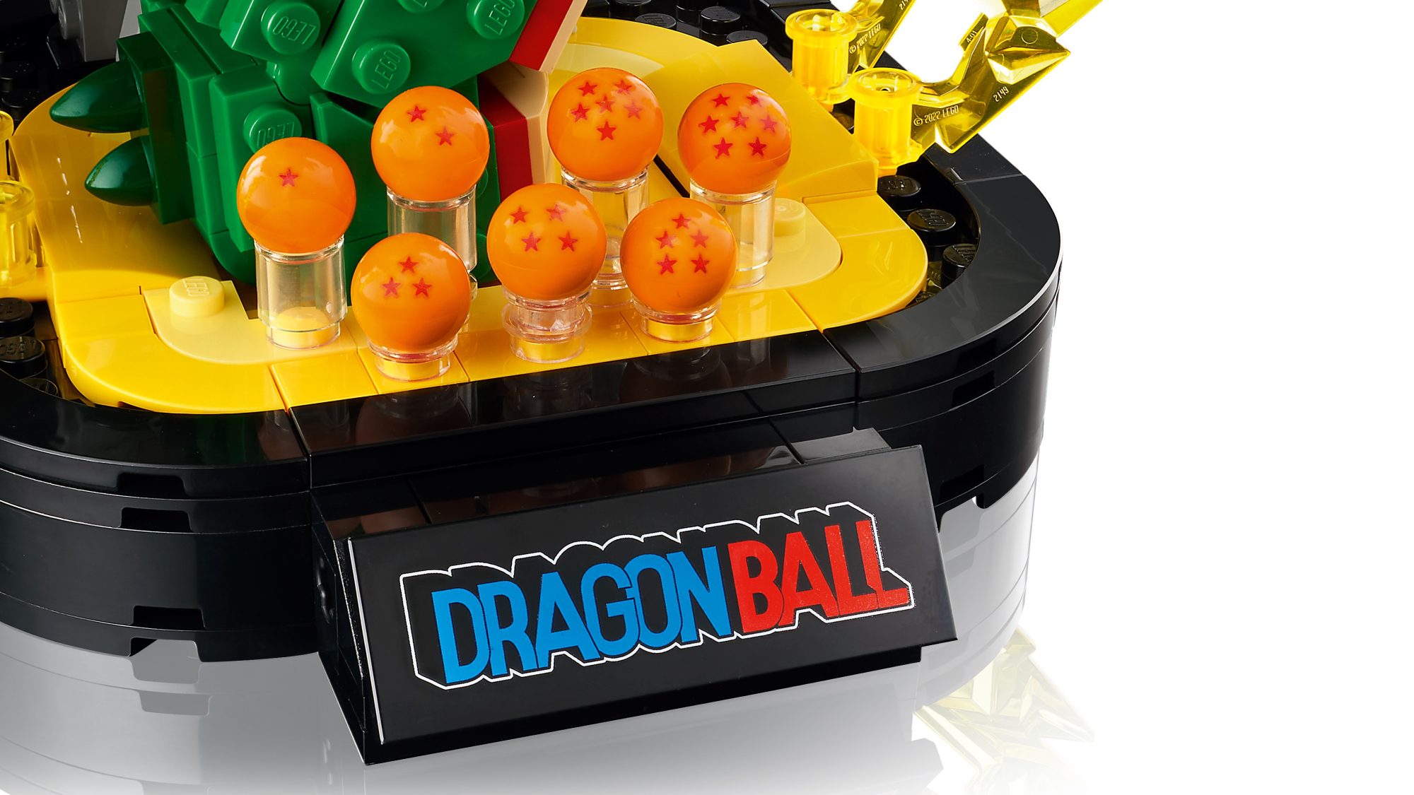 LEGO Dragon Ball set featuring orange Dragon Balls with red stars on yellow display stand with green and black elements.