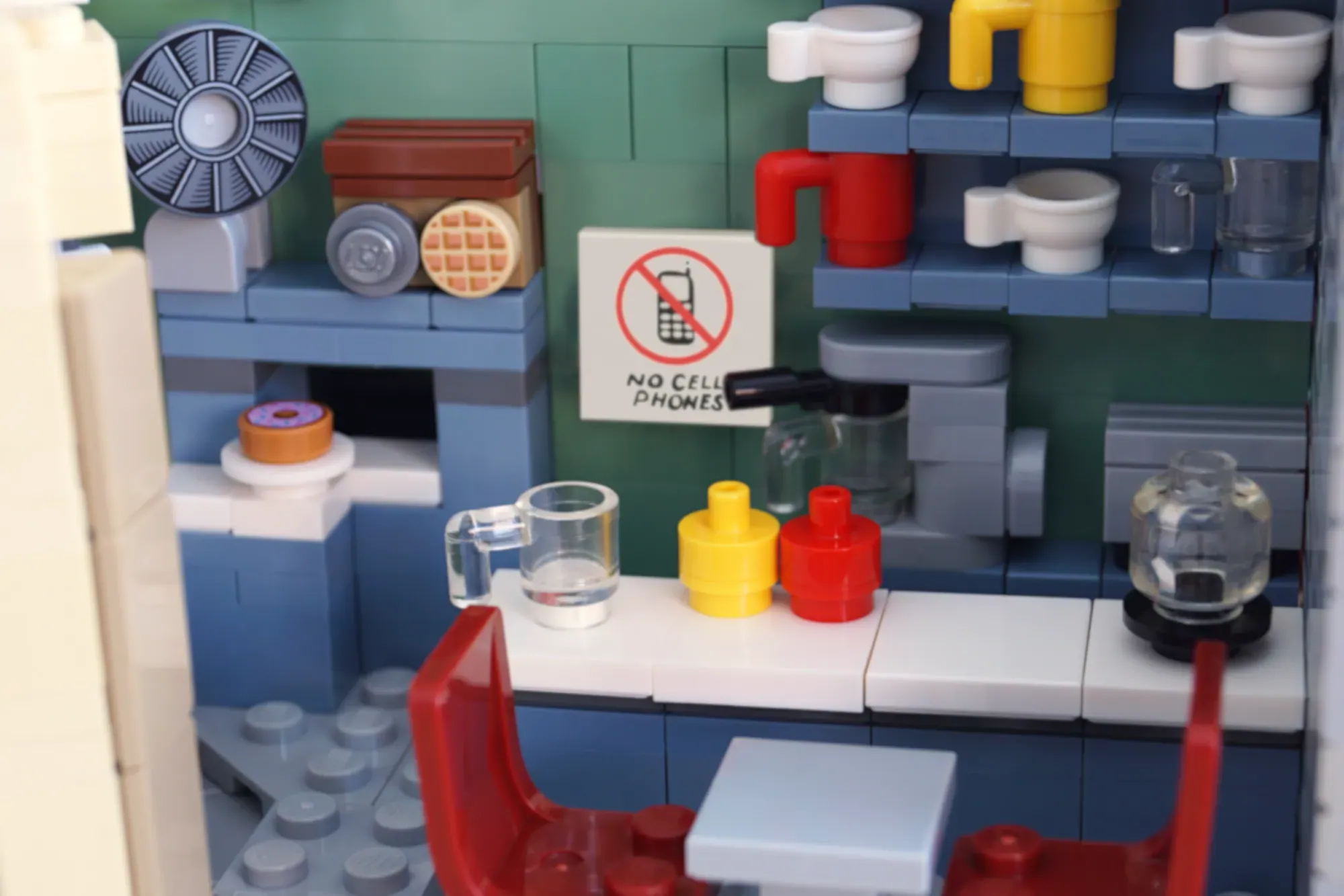 LEGO Luke's Diner interior with counter, stools, appliances, and "No Cell Phones" sign.
