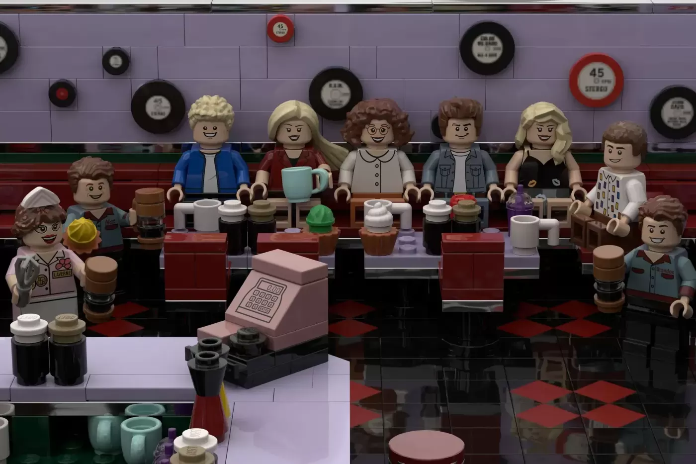 LEGO minifigures seated at a diner counter with vinyl records on the wall behind them, recreating the Peach Pit from Bever…