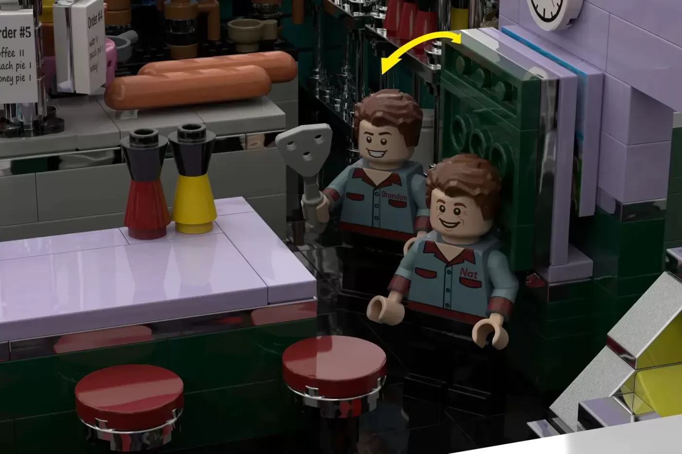 LEGO Peach Pit diner set with two minifigures in server uniforms behind counter with stools and condiments.