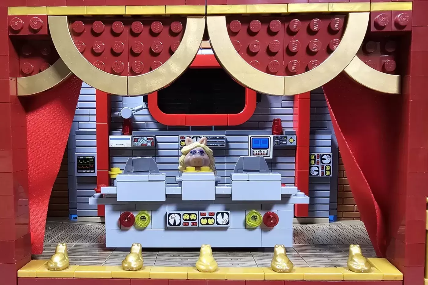 LEGO Muppet Theatre set with Miss Piggy minifigure at control panel, red curtains, and gold pig statues.