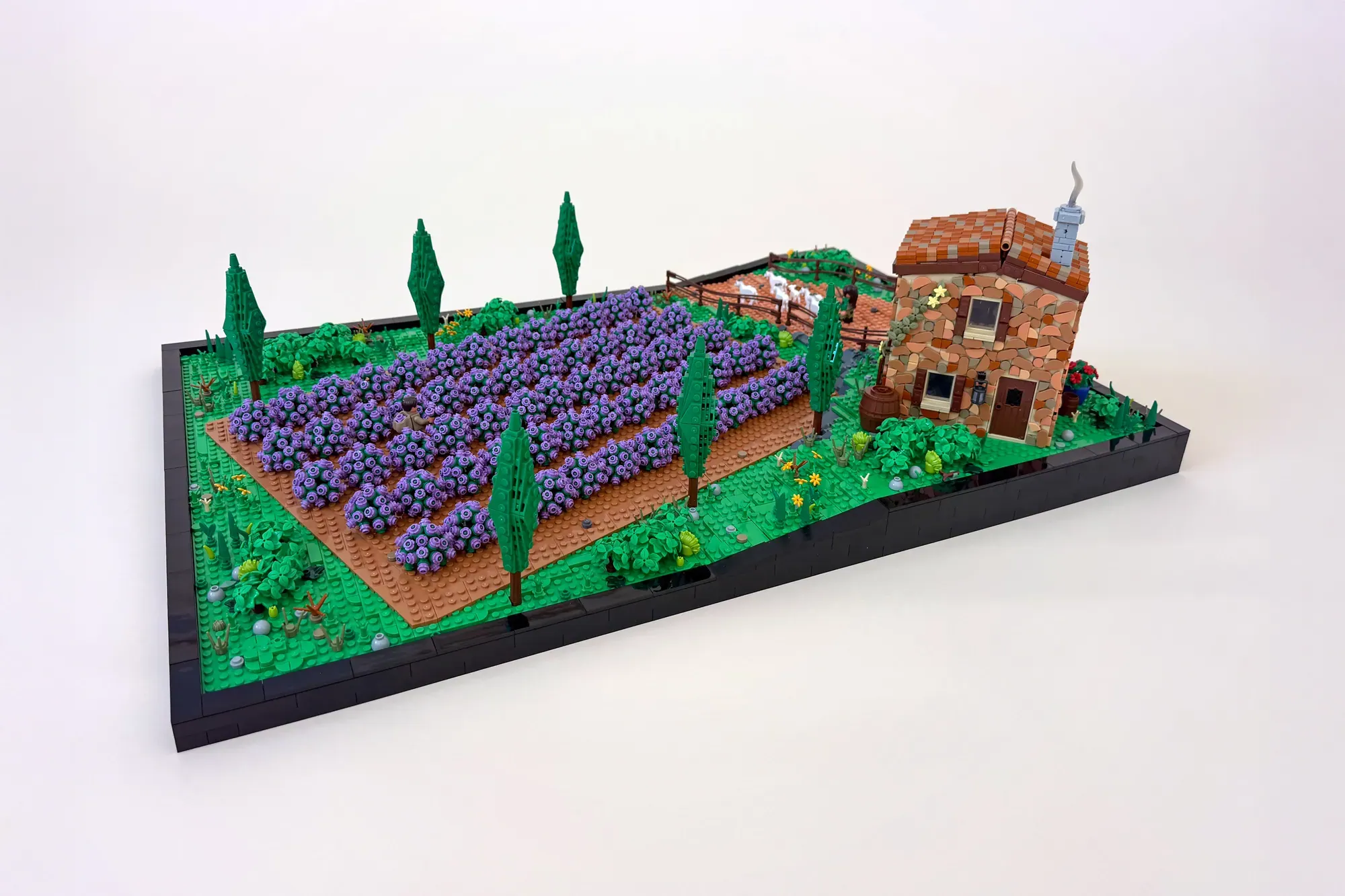 LEGO lavender field diorama with purple flower rows, cypress trees, brick farmhouse, and countryside landscape.