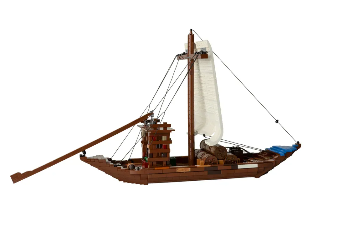 LEGO Barco Rabelo model with brown hull, cream sail, wooden cargo details, and rigging on white background.