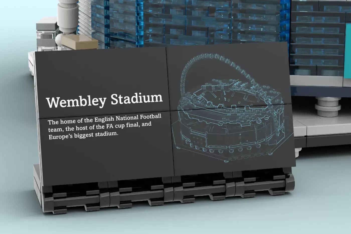 LEGO display showcasing Wembley Stadium with text description and architectural blueprint on dark panels.