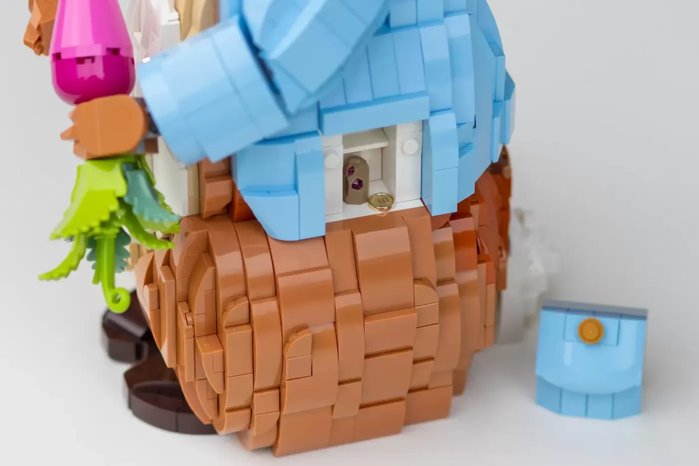 LEGO cottage with blue roof, brown wooden walls, and clothesline with colorful garments hanging above.