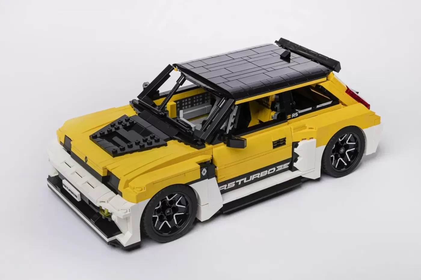 LEGO Renault 5 Turbo 3E yellow and white car model with open hood and roof rack details.
