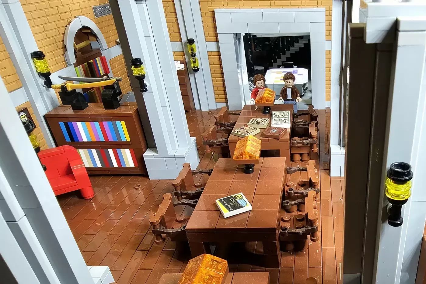 LEGO bunker interior with two minifigures at desk, brown tiled floor, mirror, red chair, and yellow lanterns on walls.