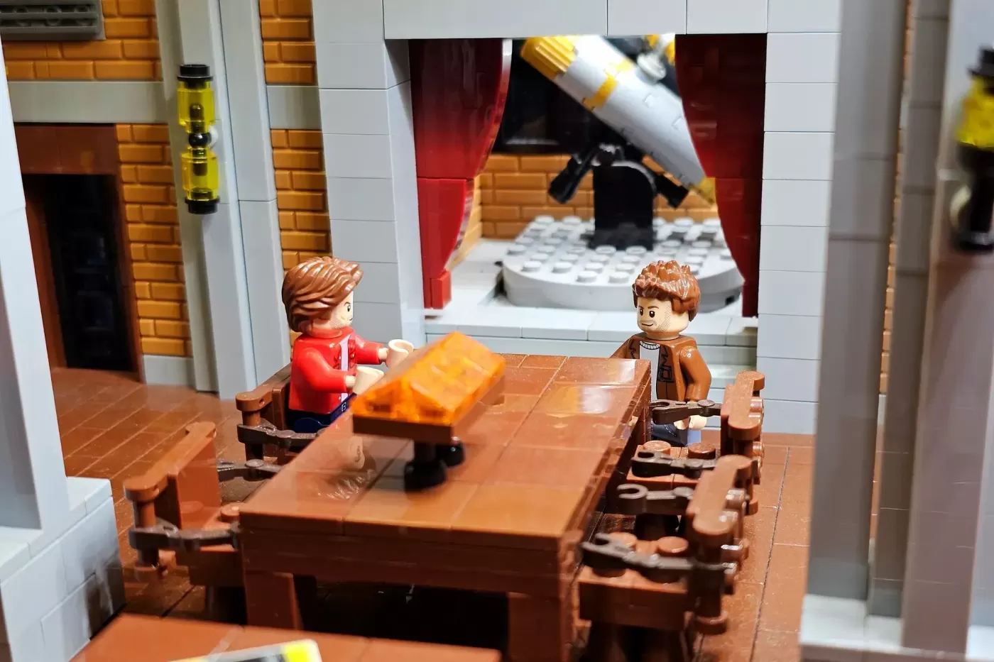 LEGO minifigures in a brick bunker room with wooden table, red curtains, and telescope in background.